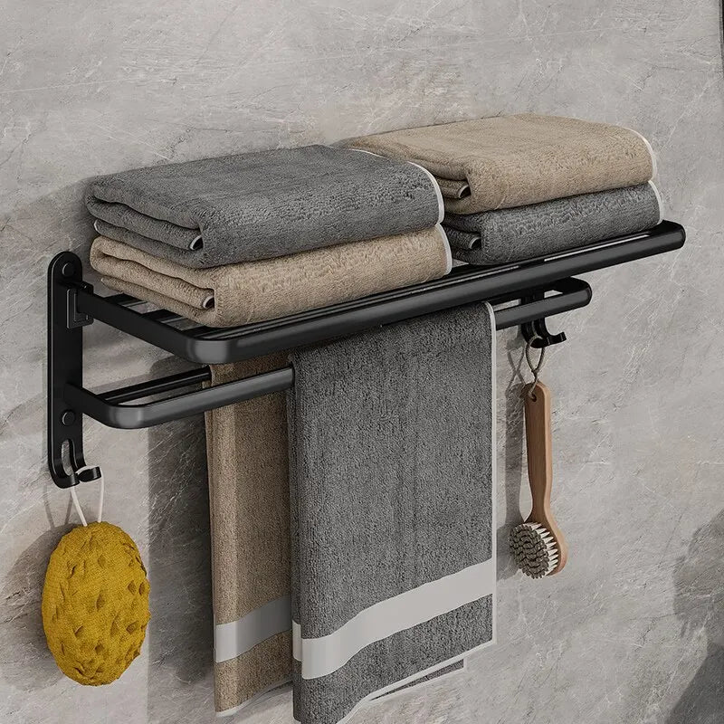 Matte black folding aluminium towel rack with towels, hook, and bath accessories for modern bathroom organization.