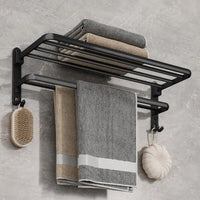 Matte black folding aluminium towel rack with towels and a brush, modern bathroom storage solution.