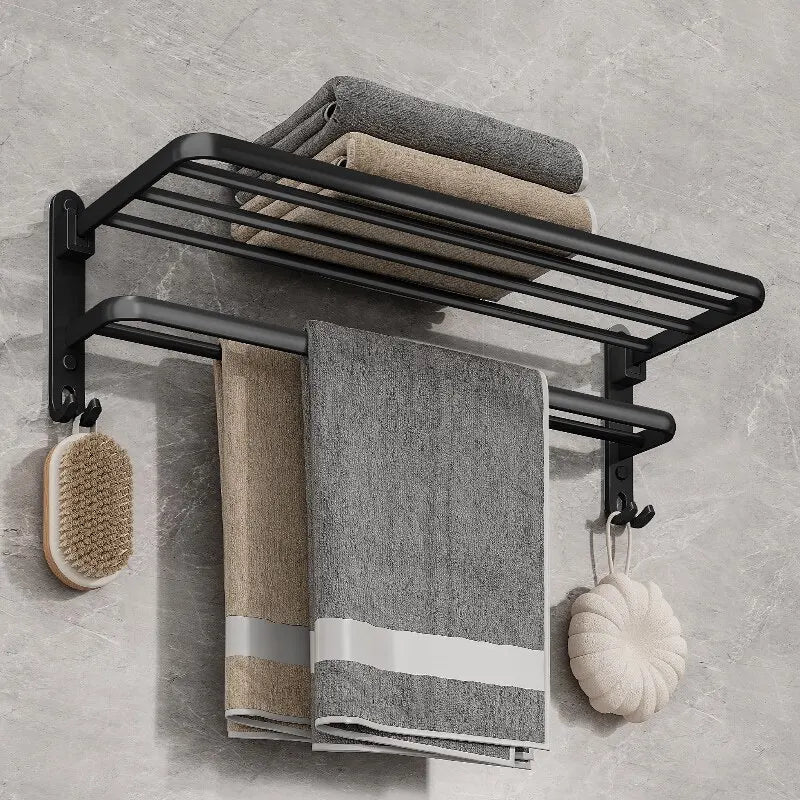 Matte black folding aluminium towel rack with towels and a brush, modern bathroom storage solution.