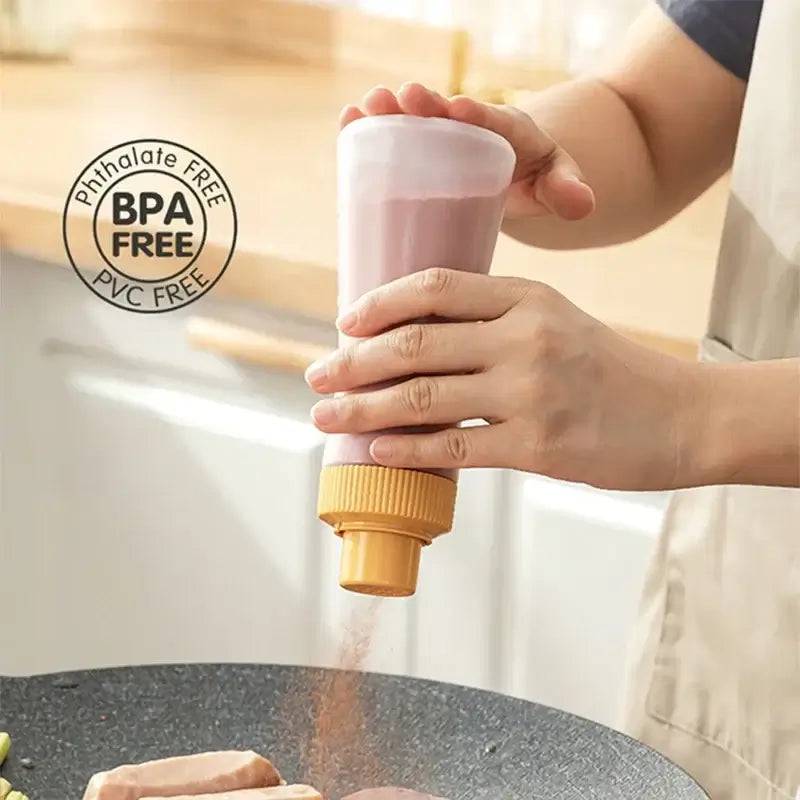 Hand holding a BPA-free condiment dispenser pouring seasoning onto a skillet for cooking.