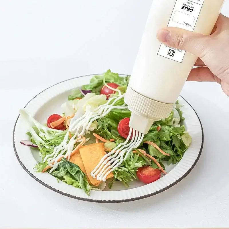 Hand pouring creamy sauce from a Multi-Purpose Condiment Dispenser onto a fresh salad.