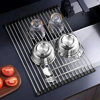 Foldable stainless steel draining rack with dishes, glasses, and utensils for efficient kitchen organization.