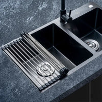 Foldable stainless steel draining rack positioned over a modern kitchen sink, enhancing space-saving kitchen organization.