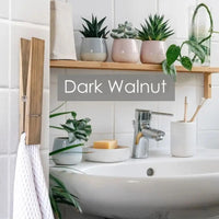 Dark walnut wooden towel clip with plants and decor in a stylish bathroom setting.