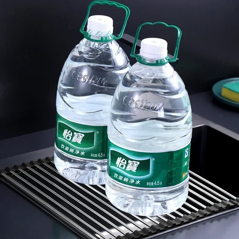 Two bottles of water on a stainless steel draining rack, highlighting efficient kitchen organization and space-saving design.